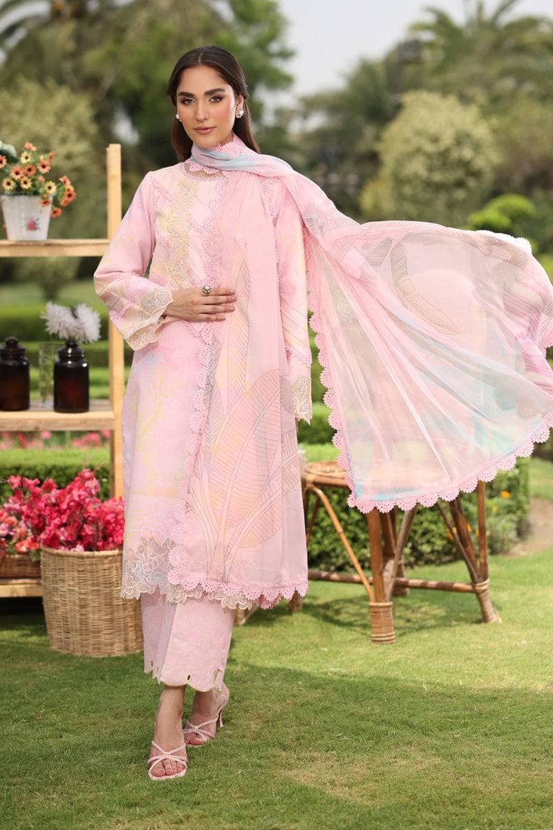 Woman in a pink traditional outfit standing outdoors with greenery and flowers in the background