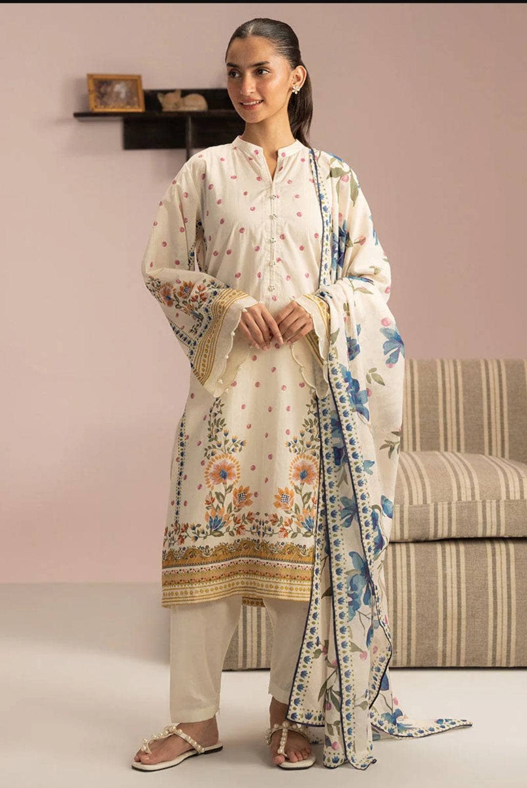 Woman wearing a traditional outfit with a floral shawl in a room setting.