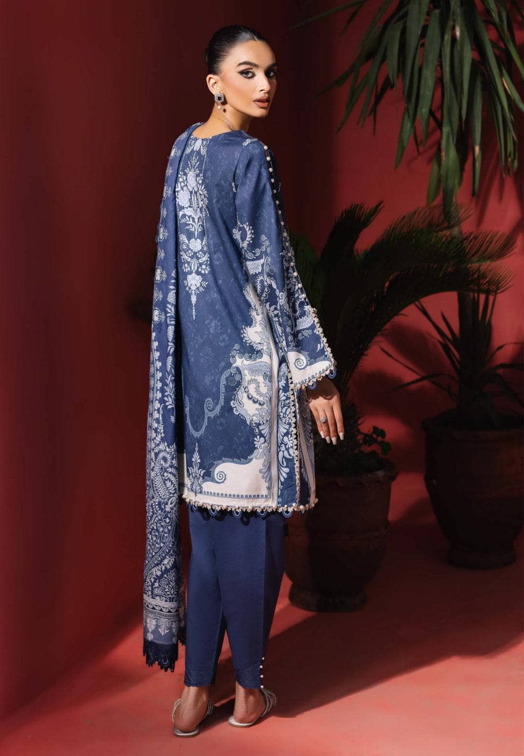 Woman wearing a blue embroidered outfit against a red background