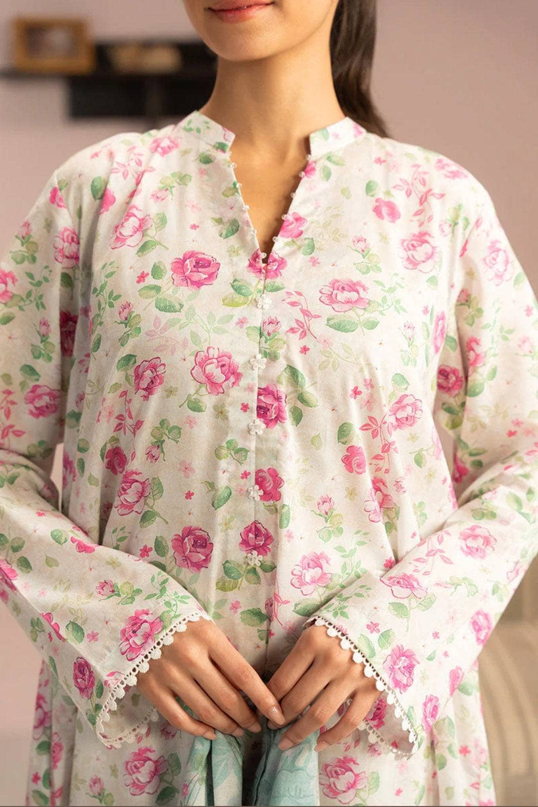Woman wearing a floral dress with pink roses and green leaves on a light background
