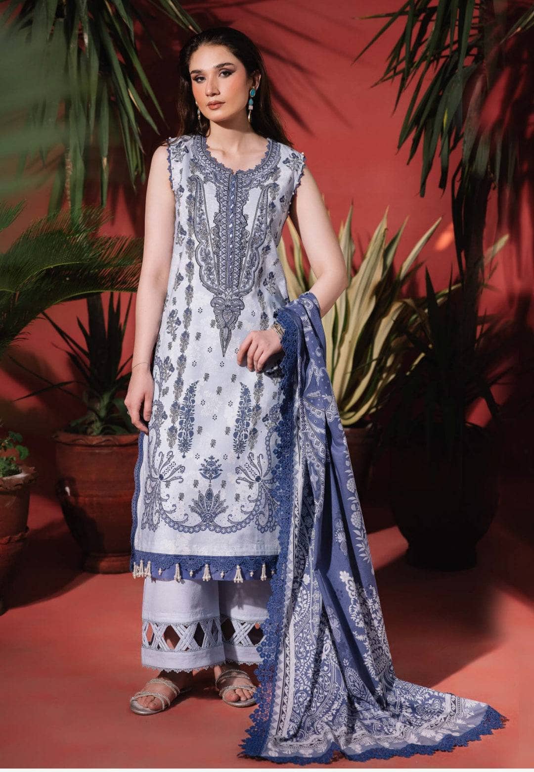 Woman wearing a blue and white embroidered traditional outfit with a red background
