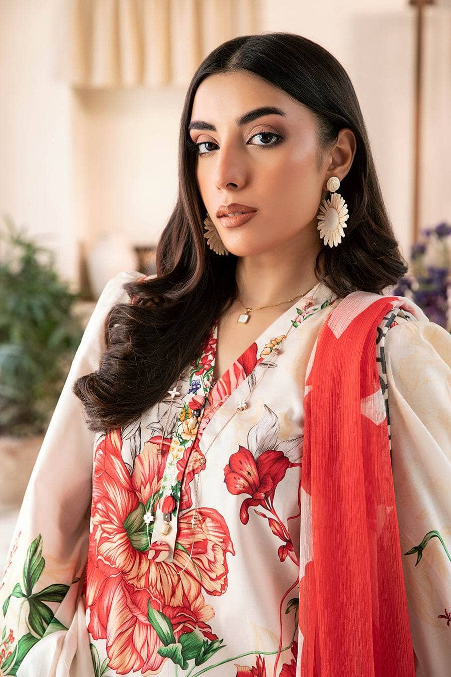 Woman wearing a floral blouse with a red scarf in an indoor setting