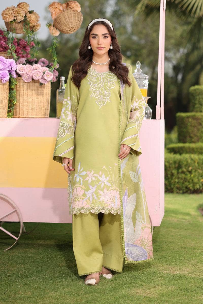Woman in a green embroidered outfit standing outdoors with flowers and a pink cart in the background