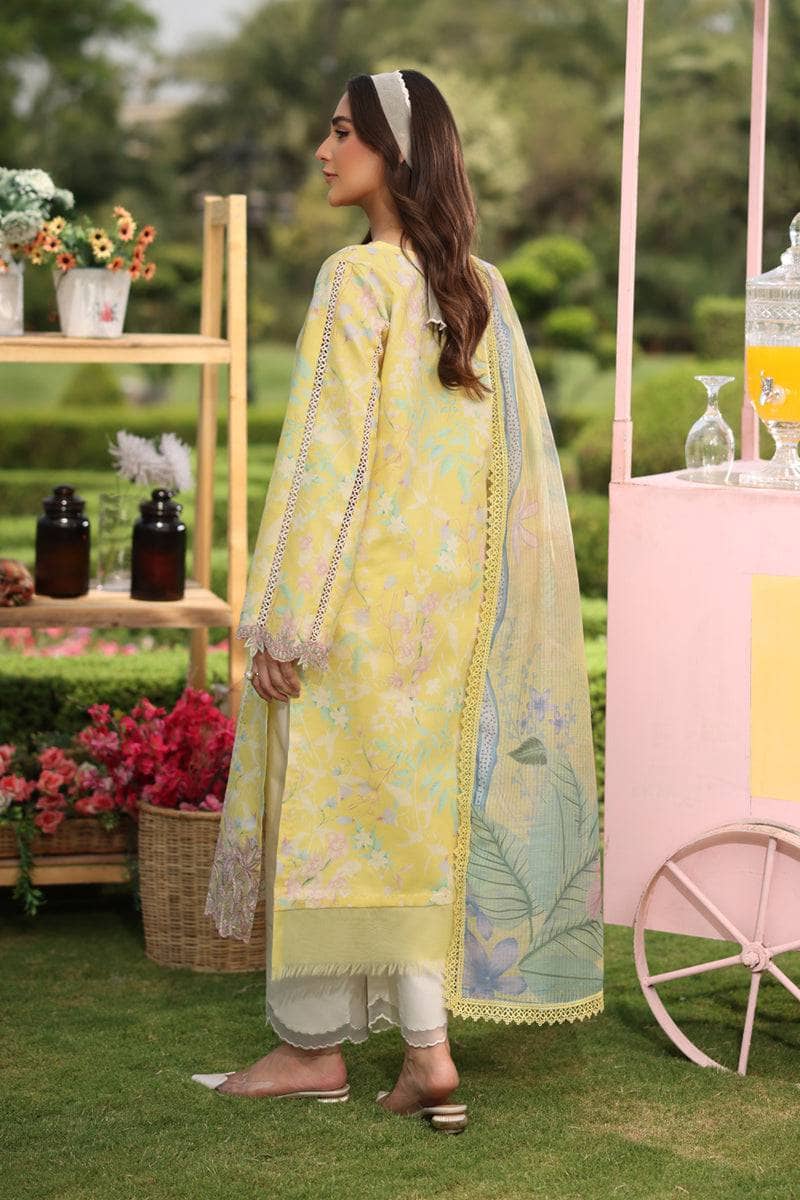 Woman in a yellow and green traditional outfit standing outdoors with floral decorations and a pink cart.
