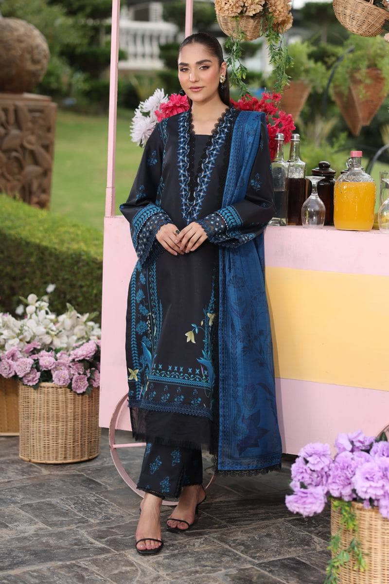Woman in traditional attire standing in a garden setting with flowers and a table in the background.
