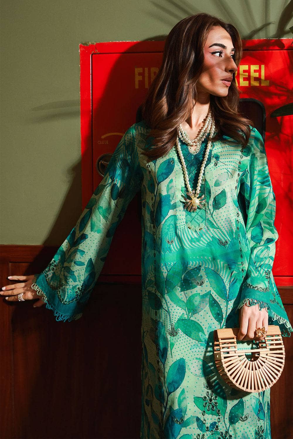 Woman in a green patterned dress standing in front of a red door.