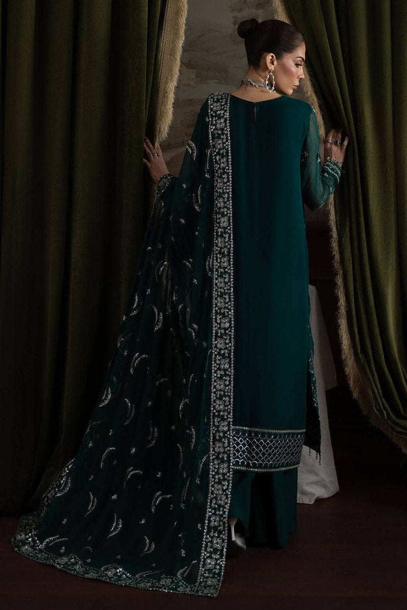 Woman in a teal traditional outfit with a black and white patterned dupatta standing in front of green curtains.
