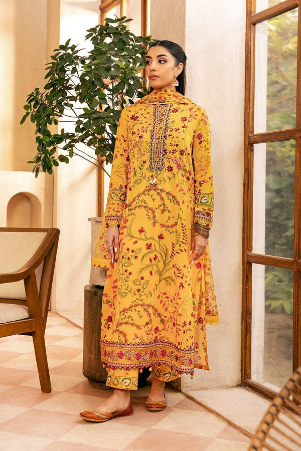 Woman in a yellow embroidered outfit standing indoors with a plant and chair in the background