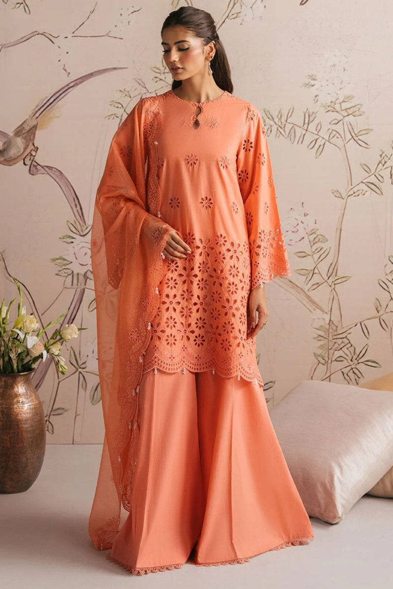 Woman wearing an orange embroidered outfit in a decorated room.