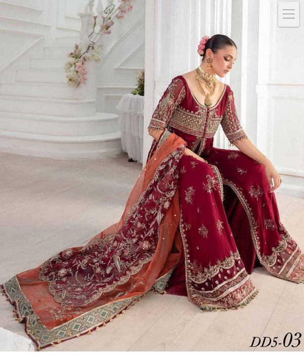 Woman in a red embroidered traditional outfit sitting on a white floor.