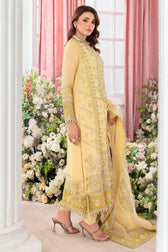 Woman in a yellow embroidered traditional outfit standing in a decorated room with pink curtains and floral arrangements.
