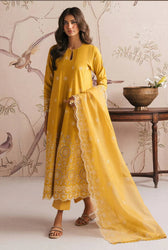 Woman in a yellow traditional outfit standing against a decorative wall.