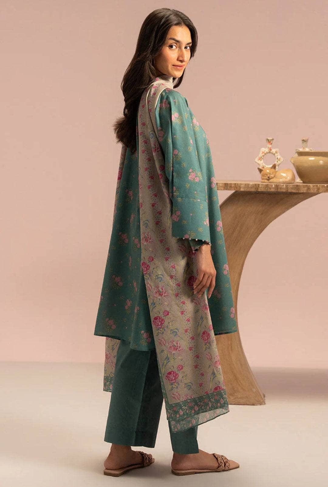 Woman wearing a teal floral outfit with a pink background