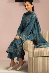 Woman in a blue traditional outfit sitting on a striped chair against a pink wall.