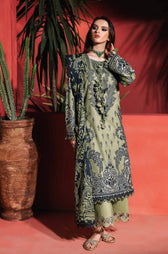 Woman in a patterned outfit standing against a red wall with a plant.