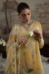 Woman in a yellow embroidered outfit holding a white flower against a blurred background