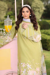 Woman in a green embroidered dress standing outdoors with a blurred background