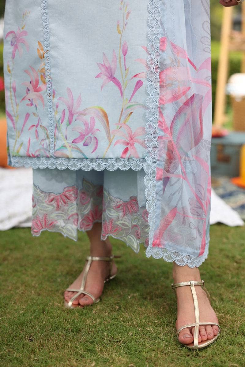 Person wearing a light blue floral dress with pink flowers on a grassy background