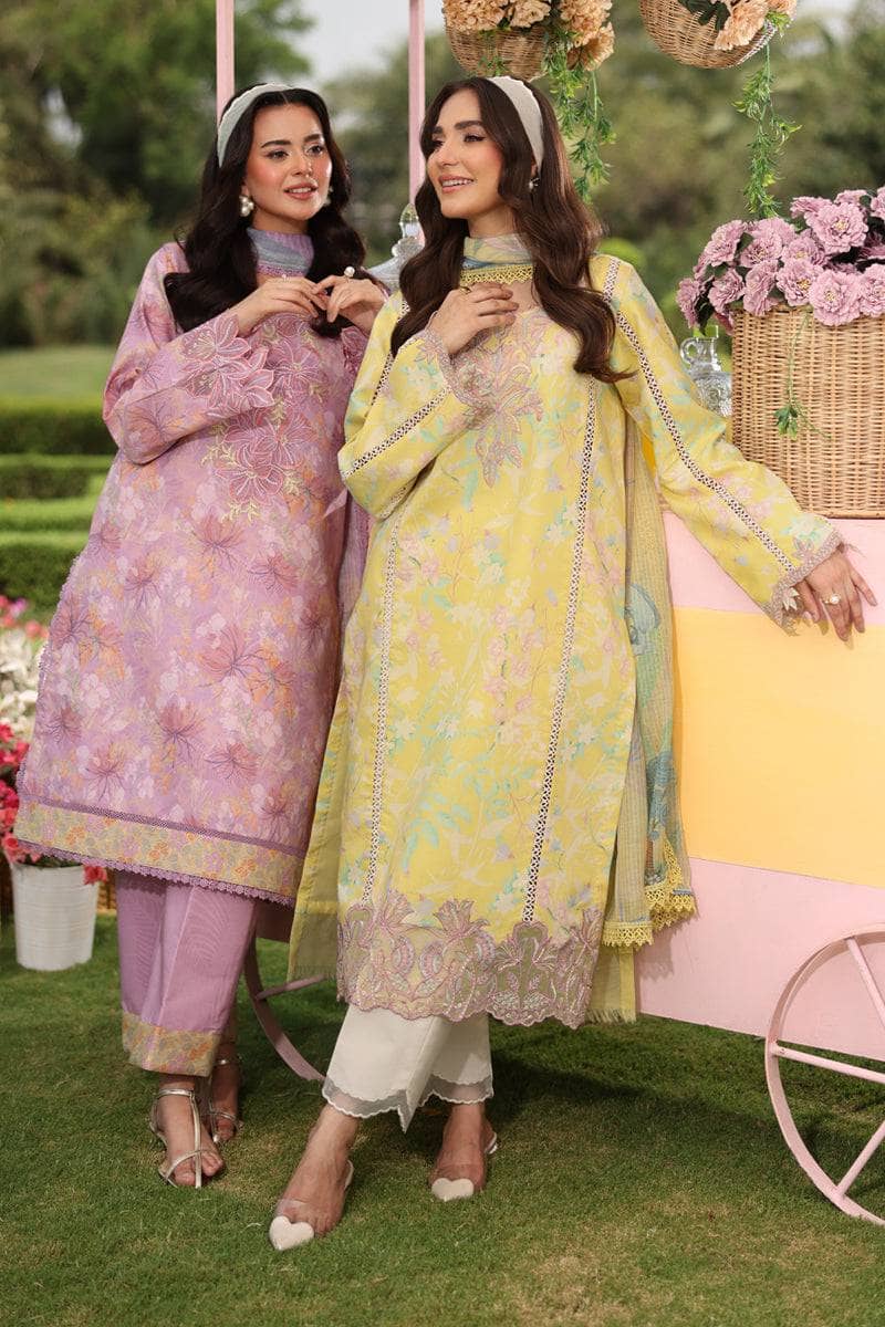 Two women in traditional outfits standing outdoors with a decorative cart and flowers in the background.