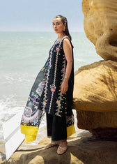 Woman in traditional outfit standing on a rocky beach with ocean in the background